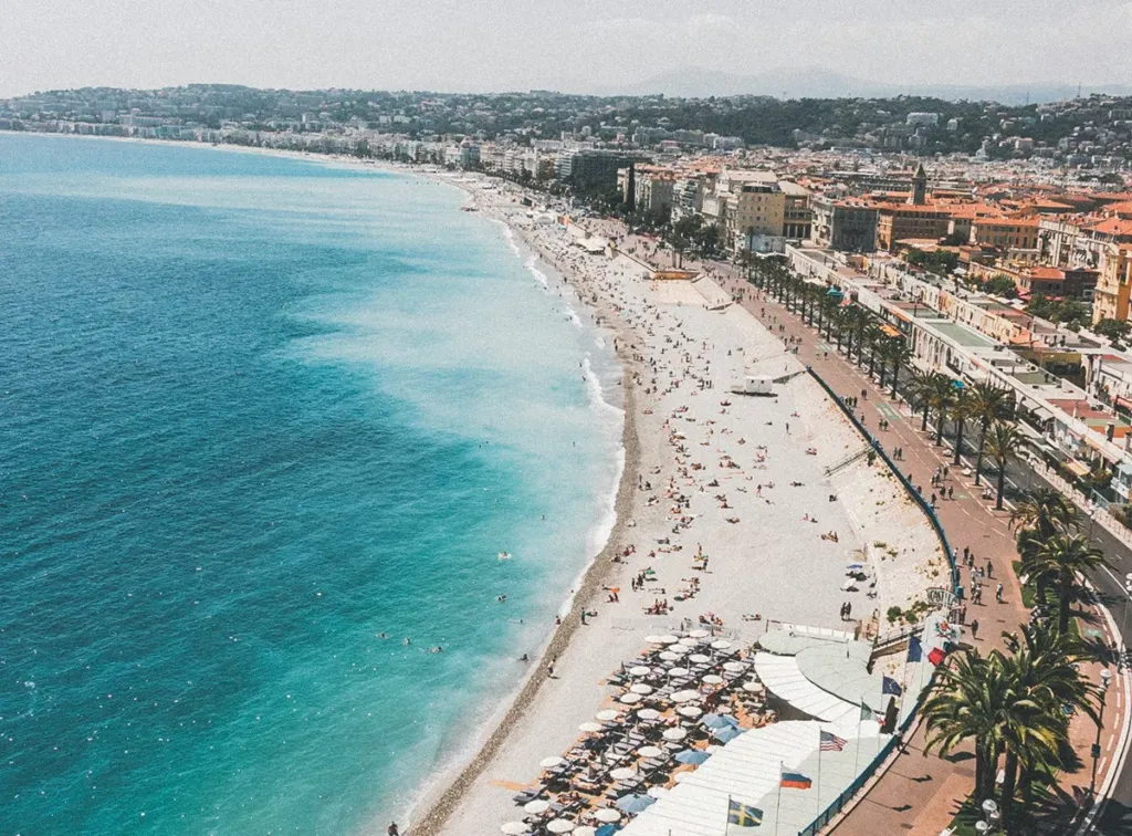 Vue aérienne de la Promenade des Anglais et de la plage de Nice avec mer turquoise et vacanciers.