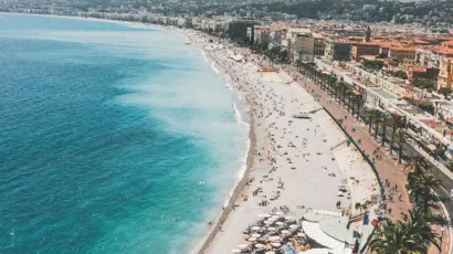 Vue aérienne de la Promenade des Anglais et de la plage de Nice avec mer turquoise et vacanciers.